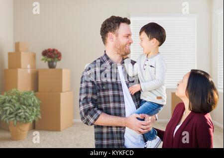 Jungen gemischten Rennen kaukasischen und chinesischen Familie im leeren Raum mit beweglichen Kästen. Stockfoto