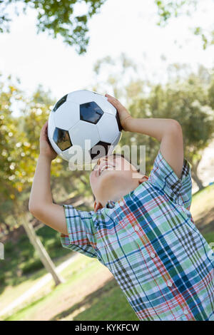 Süße junge mit Fußball im Freien im Park zu spielen. Stockfoto