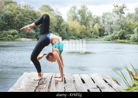 Mädchen gymnast tun eine Übung Brücke am River Bank Stockfoto