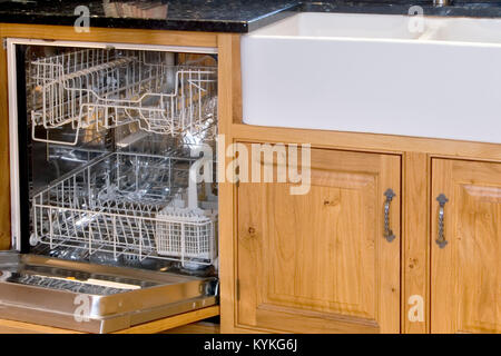 Leere offene Spülmaschine neben Waschbecken und Küchenschränke Stockfoto