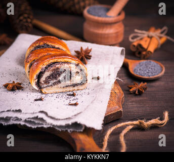 Poppy Roll auf grauem Leinen Servietten und Mohn in einem Löffel aus Holz, in der Nähe Stockfoto