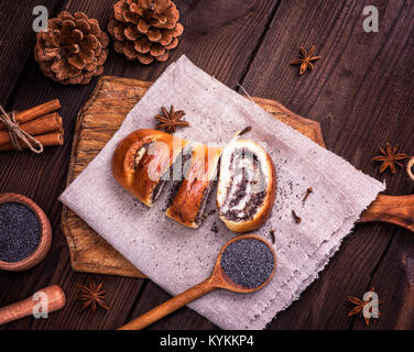 Mohn Brötchen in Scheiben geschnitten auf grauem Leinen Servietten und Mohn in einem Kochlöffel, Ansicht von oben Stockfoto