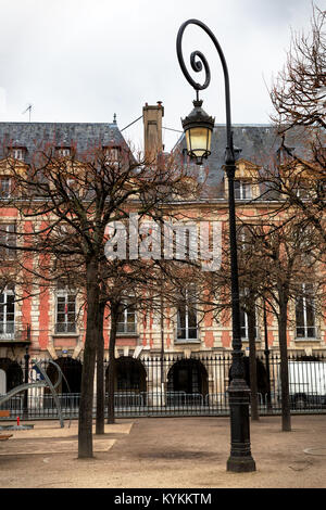 Paris Place des Vosges schönen Platz, der ältesten der Stadt. Reich verzierte Wendeltreppe Strassenlaterne im Vordergrund. Winter scene Stockfoto