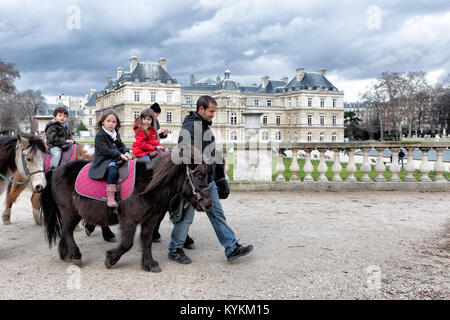 PARIS - Jan 4, 2014: Nicht identifizierte Kinder reiten Ponys bei den Luxembourg Gärten, eine beliebte Aktivität für junge Besucher in den Park, das 2. größte in Paris Stockfoto