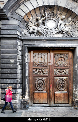 Paris großen alten geschnitzten verzierten Fassade Türen aus Holz. Historischen Viertel Marais. Frau geht durch auf Ihr Telefon. Stockfoto