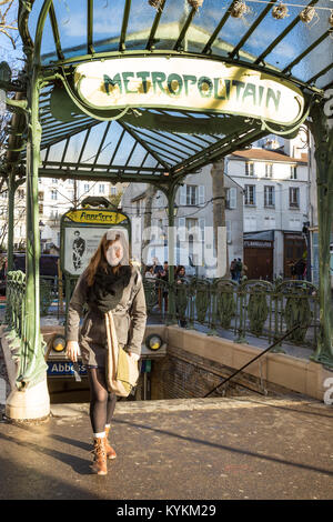 Paris, Frankreich. Eine schöne Frau geht aus dem Eingang zum berühmten Jugendstil mit der U-Bahn Station am Place des Abbesses in Montmartre. Stockfoto