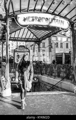 Paris, Frankreich. Eine schöne Frau am Eingang des berühmten Jugendstil mit der U-Bahn Station Abbesses in Montmartre. Schwarz und Weiß Stockfoto