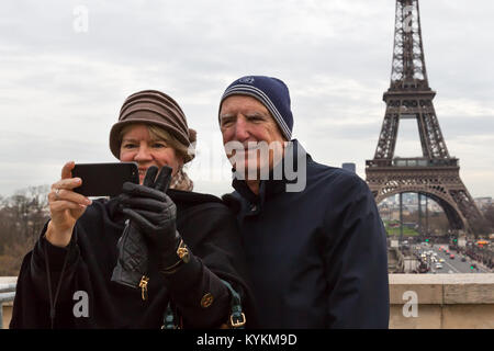 Paris Frankreich senior touristische Paar ein cellphone selfie mit dem Eiffelturm im Hintergrund. Lächeln Sie und stellen für den Schuss. Stockfoto