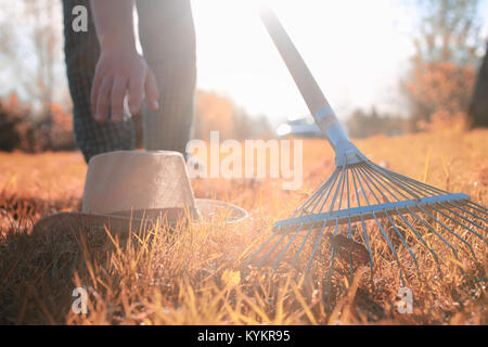 Mann mit Rechen im Herbst alten Rasen Stockfoto