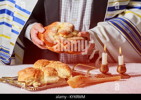 Glühende Sabbat Kerzen selektiven Fokus Nahaufnahme auf zwei Kerzen im kerzenständer. Challah und kiddusch Komposition. Stockfoto