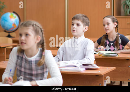 Schule Kinder am Schreibtisch in der Volksschule Lektion Stockfoto