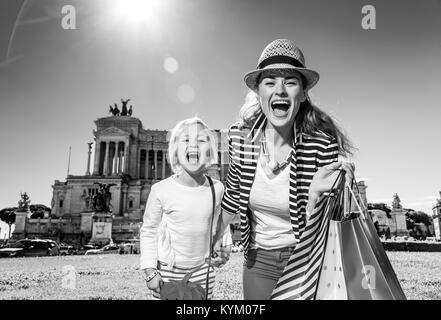 Urlaub in Rom. Portrait von lächelnden moderne Mutter und Kind Reisende in der Vorderseite des Palazzo Venezia in Rom, Italien, mit Tüten Stockfoto