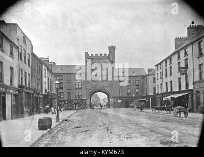 Ein Bild, das ein Dilemma in Clonmel, County Tipperary, zeigt, wo eine historische Burgstruktur und Verkehrshindernisse erfasst werden. Die Aussicht umfasst das Westtor, die Hauptwache und ein Gebäude im Tudor-Revival-Stil mit einer zinnenbefestigten Attika entlang der O'Connell Street, die Teil der Eason Collection ist. Stockfoto