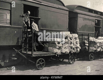 Ein Bild aus dem Jahr 1925, auf dem Postsendungen in einen Wagen des Eisenbahnpostamtes (RPO) geladen werden, ein historischer Dienst für den Transport von Postsendungen durch das US-Eisenbahnsystem. Stockfoto