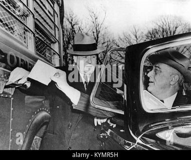 Ein historisches Foto, das Präsident Franklin D. Roosevelt zeigt, wie er einen Brief in einen Autobahnpost-Bus legt, ein ikonisches Bild, das die Rolle der mobilen Postdienste im 20. Jahrhundert repräsentiert. Stockfoto