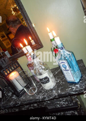 Leeren Geist Flaschen als Kerzenhalter auf einem Mantel Stück in einem englischen Pub in Durham, England verwendet wird. Stockfoto