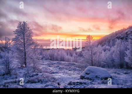 Gelb-rosa Sonnenuntergang über Schnee - Berg, Wald, Häuser und Schacht Stockfoto