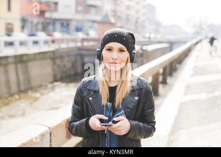 Portrait junge Frau schöne blonde Haare outdoor wandern Musik hören mit smart phone Hand halten - Musik, entspannend, Technologie, Konzept Stockfoto