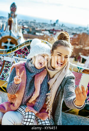 Barcelona-Handschrift. Porträt des Lächelns moderne Mutter und Tochter Reisende am Park Güell in Barcelona, Spanien mit dem Handy nehmen Selfie wh Stockfoto