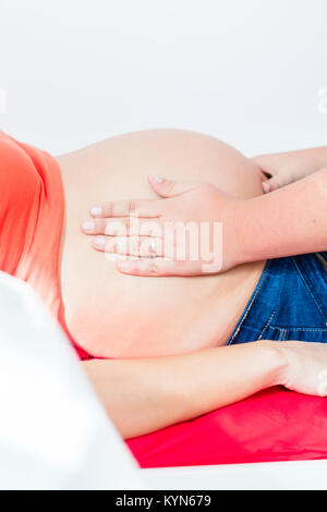 Hebamme exanimating Bauch der schwangeren Frau manuell Stockfoto