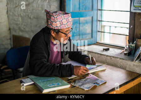 Die Sekretärin schreibt Informationen über den Touristen zu einem Buch im Büro im Dorf Dhampus, Nepal, Asien. Annapurna Base Camp Trek. Stockfoto