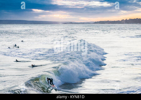 Golden Sunset über Bournemouth Strand/Meer mit Surfer Genießen der guten Swell, Bournemouth, Dorset, England, Großbritannien Stockfoto