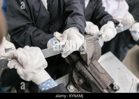 Children's Master Class im Auto Service. Bügeleisen Schraubenschlüssel in der Hand schraubt die große Sechskantmutter anziehen. Der schraubenschlüssel Stahl Werkzeuge für Reparatur Stockfoto