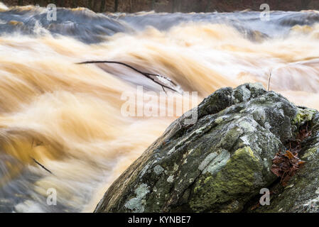 Frost und Eis auf Granitblock mit Wildwasser rapid im Hintergrund. Stockfoto