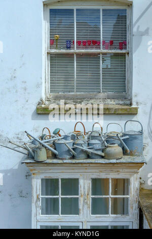 Herne Bay, England, UK. Sammlung von alten Metall Gießkannen auf dem Dach eines Fensters außerhalb eines Hauses. Stockfoto