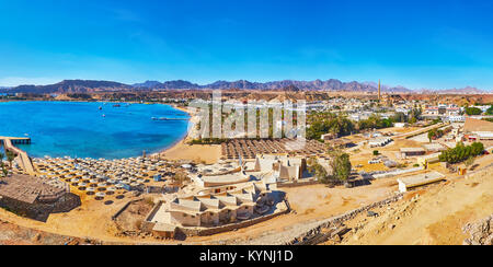 Der Berglandschaft von Sharm El Maya Bezirk mit Strand, zahlreichen Sonnenschirme, Hotels und Felsen im Hintergrund, Sharm El Sheikh, Ägypten. Stockfoto