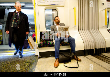 London, England, UK. Mann eine Zeitung lesen auf einer Londoner U-Bahn Stockfoto