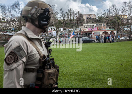 Eine Luft- und Marine Operations Agent schaut auf eine Masse, die mit einem Jungen fliegen die Puerto Rican Flag nach der Landung in Aibonito am Sonntag, den 24. September. Us-amerikanischen Zoll- und Grenzschutzbehörden Foto von Kris Grogan Stockfoto