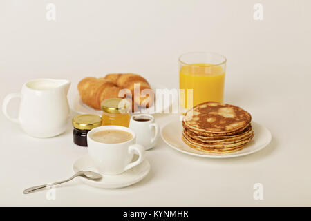 Frühstück - Kaffee mit Croissants, Saft mit Pfannkuchen auf einem weißen Hintergrund. Selektive konzentrieren. Stockfoto