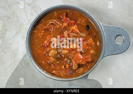 Geräuchertes Fleisch von Truthühnern und Bohnensuppe in Metall Soup Bowl. Es ist eine klassische Suppe Rezept mit geräuchertem Türkei, Tomaten, Sellerie und Zwiebeln. Stockfoto