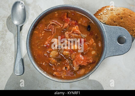 Geräuchertes Fleisch von Truthühnern und Bohnensuppe in Metall Soup Bowl. Es ist eine klassische Suppe Rezept mit geräuchertem Türkei, Tomaten, Sellerie und Zwiebeln. Stockfoto