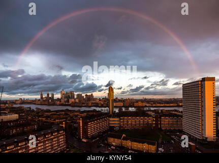 London, Großbritannien. 15 Jan, 2018. UK Wetter: Eine massive rosa/rot Rainbow bricht beim Sonnenuntergang nach einem kurzen Regenguss über South East London einschließlich Canary Wharf business park Gebäude (L) Credit: Guy Corbishley/Alamy leben Nachrichten Stockfoto