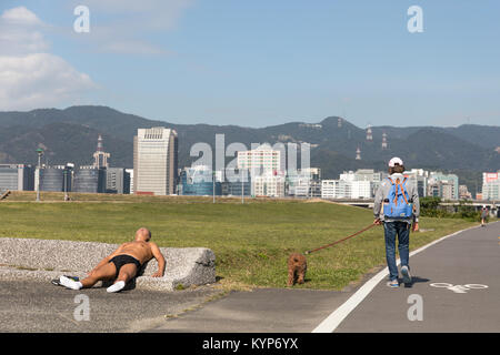 Taipei, Taiwan, 16. Jan. 2018: Eine Frau geht mit ihrem Hund als Jogger nutzt das warme Winterwetter in Taipeh zu beginnen mit dem Aufbau einer Tan am 31.01.16, da die Temperaturen in der Stadt 26,6 Grad Celsius erreicht. Credit: Perry Svensson/Alamy leben Nachrichten Stockfoto