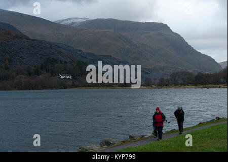 Llanberis, Gwynedd, Wales, UK. 16 Jan, 2018. Menschen gehen von Llyn Padarn in Llanberis in Gwynedd, Wales, UK. An einem kalten und windigen Morgen nach fiel Schnee auf den Gipfeln in Snowdonia letzte Nacht. Credit: Graham M. Lawrence/Alamy leben Nachrichten Stockfoto