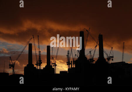 Eine Silhouette der Battersea Power Station und die umliegenden Krane bei Sonnenuntergang in London. Stockfoto