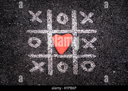 Happy Valentines Day card, Tic Tac Toe Spiel auf dem Boden, xoxo und Stein in der Form eines Herzens Stockfoto