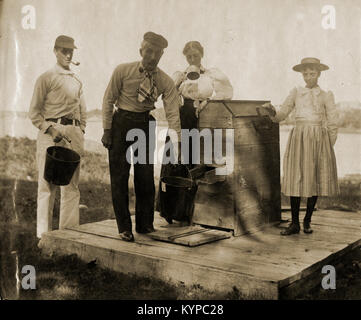 Antike ca. 1905 Foto, Familie an der Wasserpumpe mit Fluss im Hintergrund. Die Lage ist in oder in der Nähe von riggsville (jetzt Robinhood), Maine in der Sagadahoc County, USA. Stockfoto