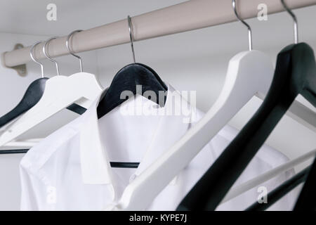Weiße und schwarze Leere Kleiderbügel im Schrank Stockfoto