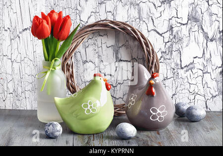 Ostern Zusammensetzung mit roten Tulpen, Keramik hühner und ostereier auf alte, gesprungene Holz Stockfoto