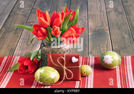 Ostern noch leben mit roten Tulpen, verpackte Geschenk und Ostereier auf hölzernen Tisch Stockfoto