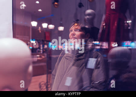 Nachdenkliche Frau durch Schaufenster in der Nacht suchen während der Weihnachten und Neujahr shopping rabatt Saison, Ultra Violet Schatten getönt Stockfoto