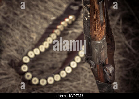 Antike Jagd Pistole mit Munition Riemen auf trockenem Gras wie Jagd Hintergrund in retro wild west Style Stockfoto