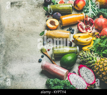 Bunte Smoothies in Flaschen mit frischen tropischen Früchten und Superfoods auf grauem Beton Hintergrund, selektiver Fokus, kopieren. Gesund, Vegetarisch, Stockfoto