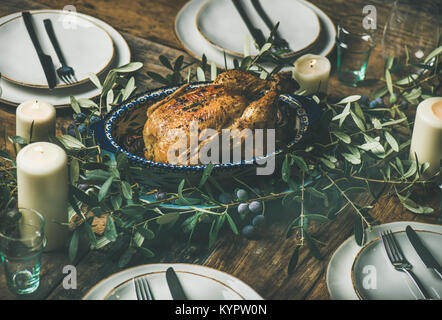 Ganzen gebratene Hähnchen mit Knoblauch für Heiligabend feiern mit Olive Tree Branch über rustikalen Holztisch Hintergrund mit Platten dekoriert und c Stockfoto