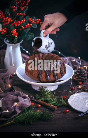 Frau gießen Ganache von Schokolade bundt Cake Stockfoto