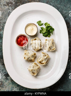 Traditionelle gedämpfte Teigtaschen Manty mit Joghurt und Tomatensauce. Stockfoto